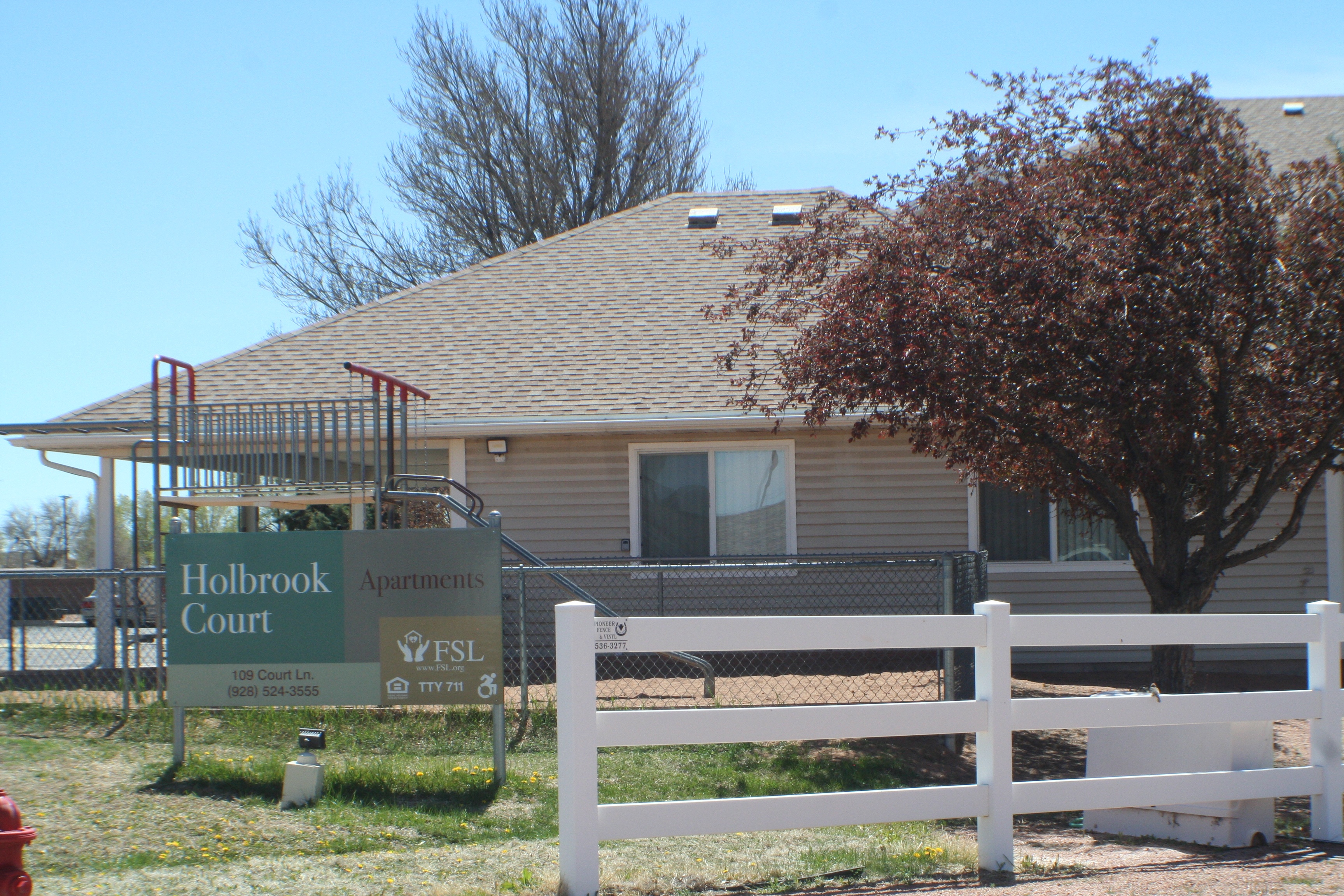 A sign for Holbrook Court apartments is in front of a building.